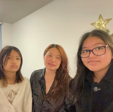 Chang family smiles inside their living room, by a Christmas tree