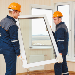 two professionals carrying a window to be installed in frame