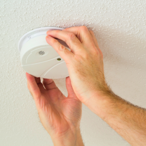 zoom in of person installing a smoke detector, hands and wrists visible